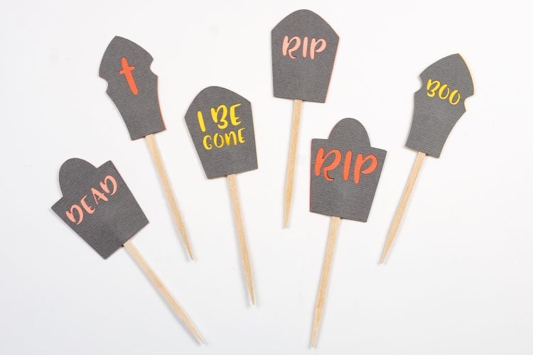 Images of Halloween graveyard cake toppers that say, "RIP", "Dead", "I Be Gone", "Dead" and "Boo"