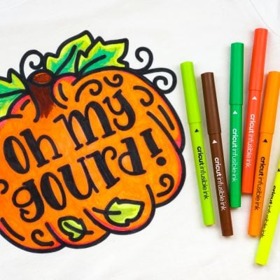A picture of a pumpkin next to several Cricut infusible ink markers.  The pumpkin says, "Oh My Gourd" on it