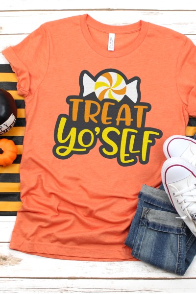 Fall decor surrounding a pair of blue jeans, tennis shoes and an orange t-shirt designed with a piece of Halloween candy and the saying, "Treat Yo'Self"