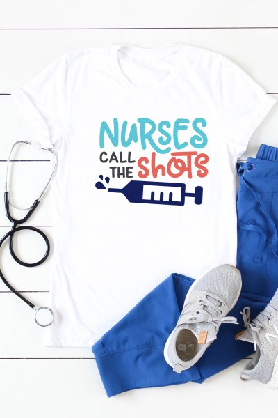 Blue hospital scrubs, tennis shoes, a stethoscope and a white t-shirt with the design of a syringe on it and the saying, "Nurses Call the Shots"