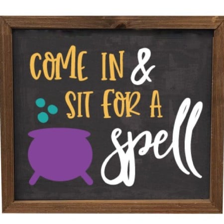 Framed sign with an image of a witches cauldron and the saying Come in and Sit for a Spell