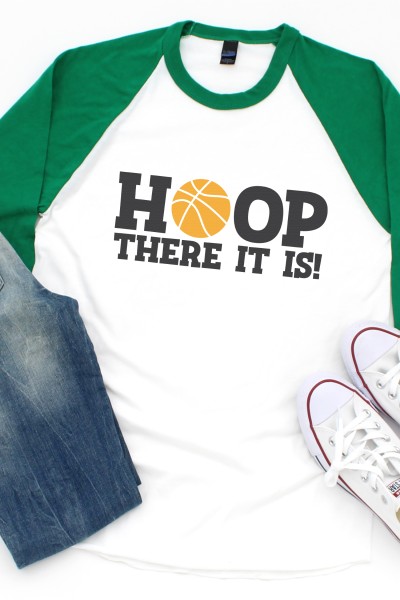 Blue jeans, tennis shoes and a baseball style shirt with blue sleeves and white body decorated with saying, "HOOP There it is!"