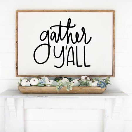 Framed white sign that says "Gather Y’all" on it