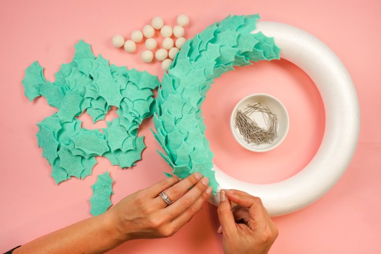 Image of hands using pins to assemble a wreath made out of felt