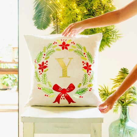 White pillow with a monogrammed Christmas wreath image on it and the letter Y