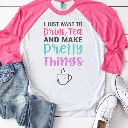 A pink and white baseball style shirt with a SVG design that says, I Just Want to Drink Tea and Make Pretty Things