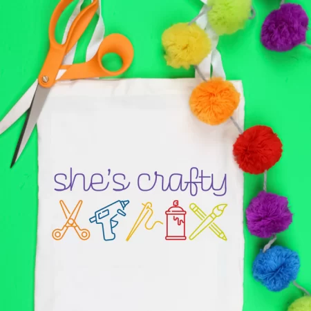White tote with a SVG design of crafting tools and the words She's Crafty