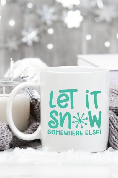 A coffee cup on a table with the saying "Let IT Snow Somewhere Else"