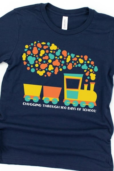 A dark colored t-shirt with a train cut out of different colored vinyl and the saying, "Chugging Through 100 Days of School!"