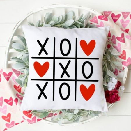 White pillow with image a tic-tac-toe game with X's, O's and red hearts