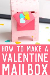 A paper Valentine's Day Mailbox with Cricut machine in background with colored hearts scattered around the mailbox and an announcement saying "How to make a Valentine Mailbox - HEYLETSMAKE STUFF.COM