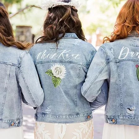 Three women wearing custom denim jackets for both the bride and the bridesmaids