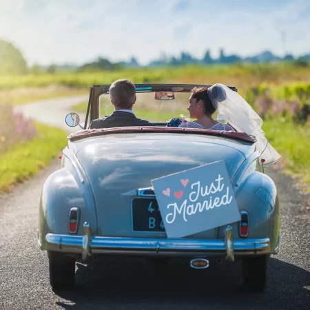 Bride and groom in a convertible car with a Just Married sign on it