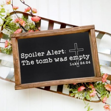 Chalkboard sign with an image of a cross and the words Spoiler Alert - The tomb was empty