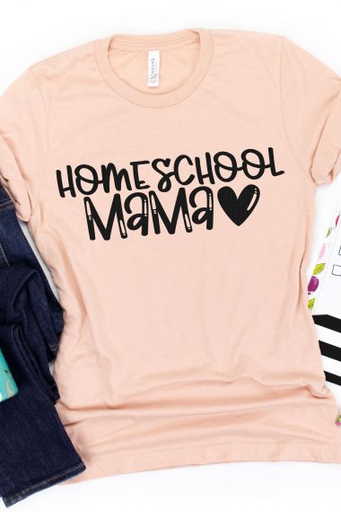 Peach colored t-shirt with the quote "Homeschool Mama" in black vinyl along with a black heart.  Shirt is paired with a pair of blue jeans, a water bottle, and a to do list with a pencil and yellow marker.
