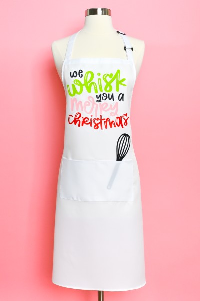 Christmas Apron and Whisk pictured with quote on apron saying "We whisk you a Merry Christmas"