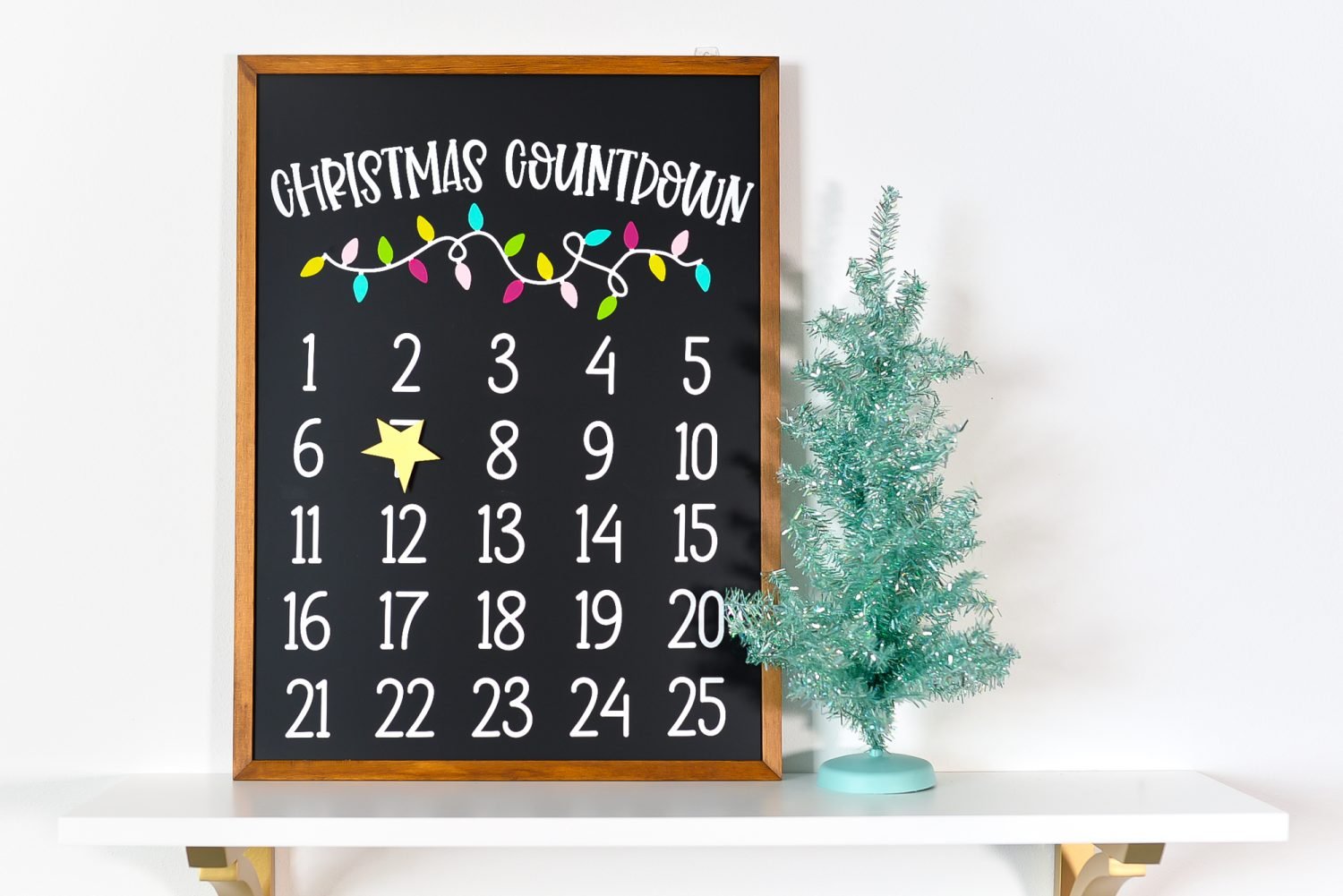 Christmas countdown calendar on a shelf with a faux Christmas tree.