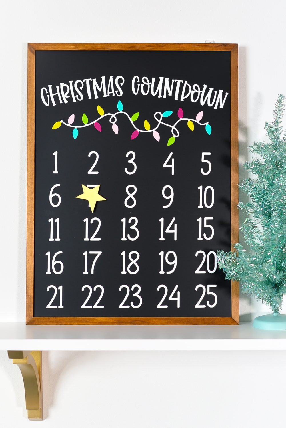 Christmas countdown calendar on a shelf with a faux Christmas tree.