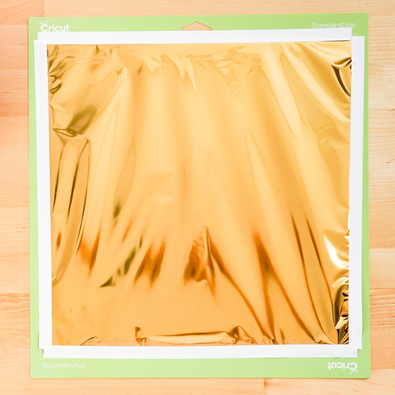 A piece of Cricut foil in gold taped to a green Cricut mat