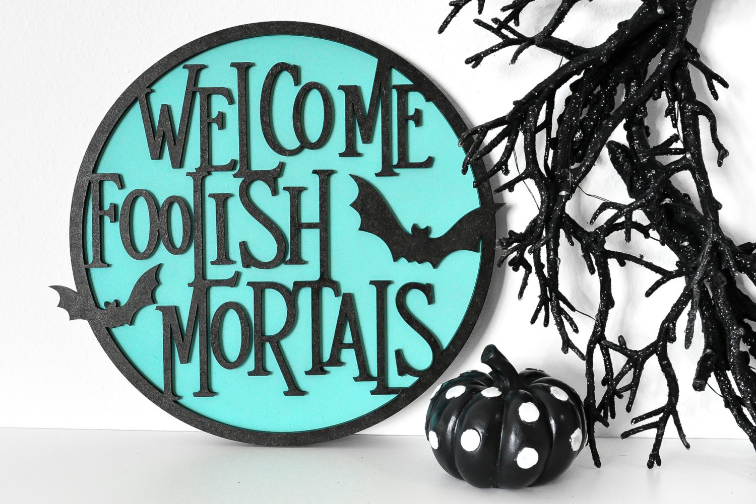 Welcome Foolish Mortals sign on a shelf with Halloween decor