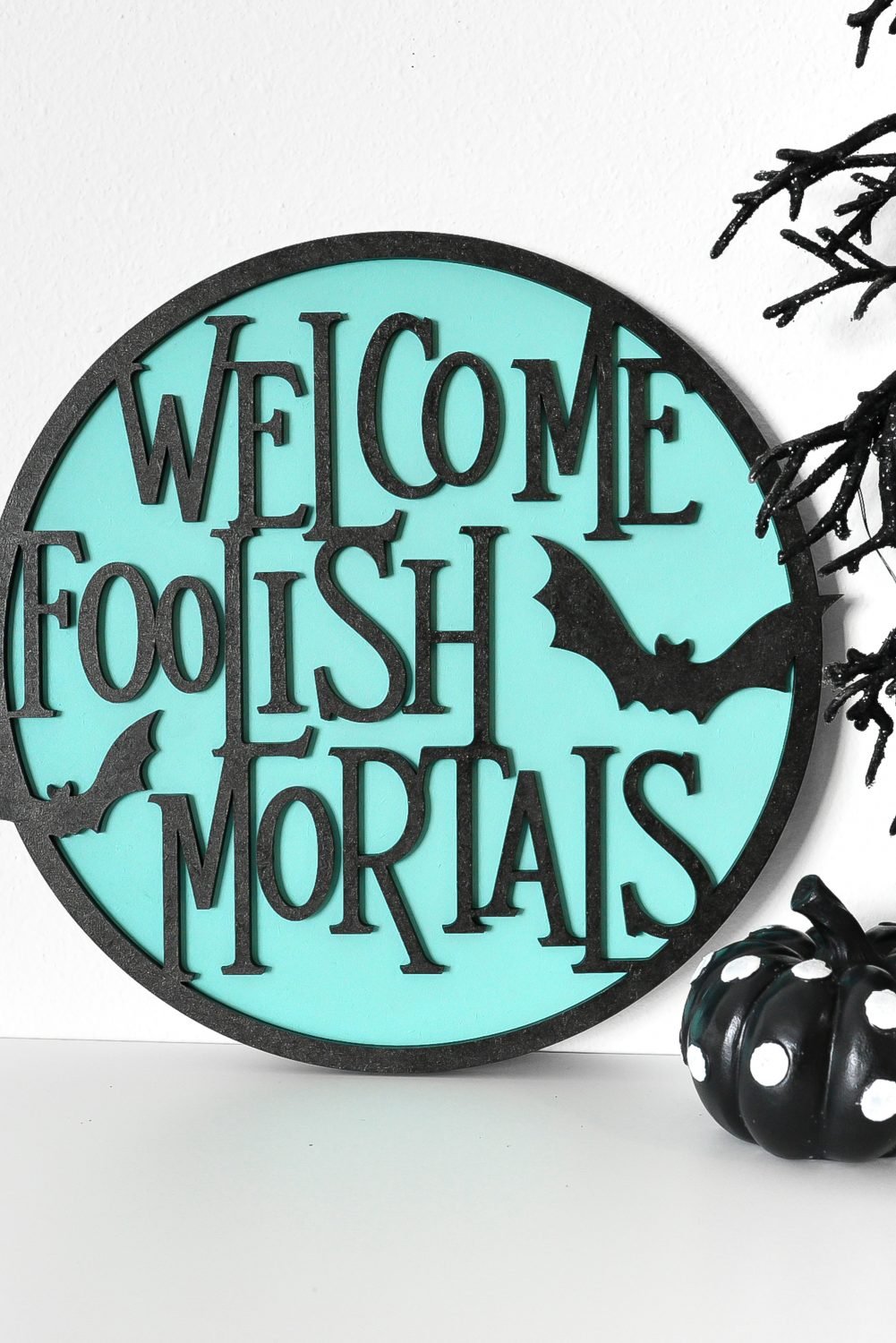 "Welcome Foolish Mortals" sign made on the Glowforge on a shelf with Halloween decor