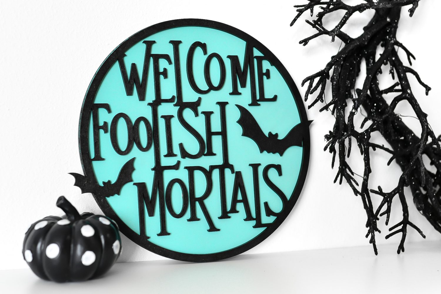 Welcome Foolish Mortals sign on a shelf with Halloween decor