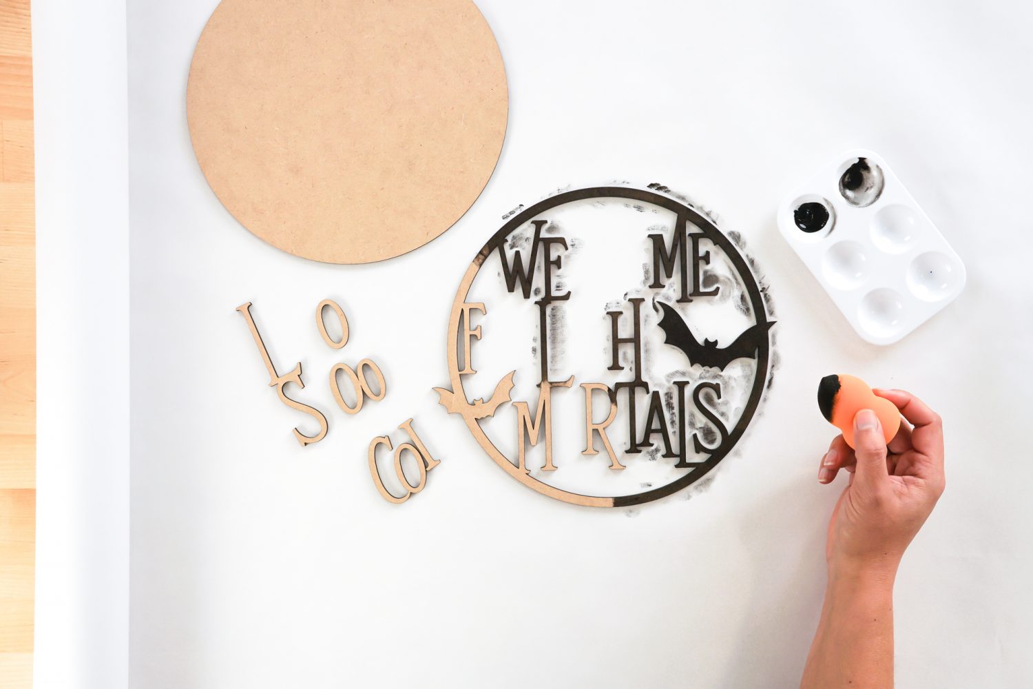 Hands painting the sign with black paint and a makeup sponge.