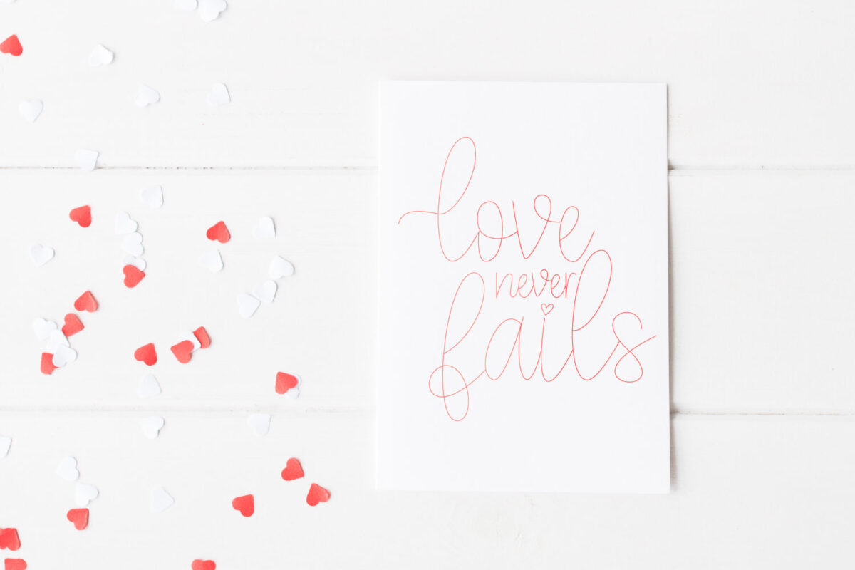 Love Never Fails foiled on a card.