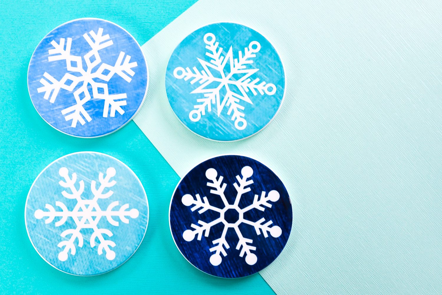 Four finished snowflake coasters on teal background