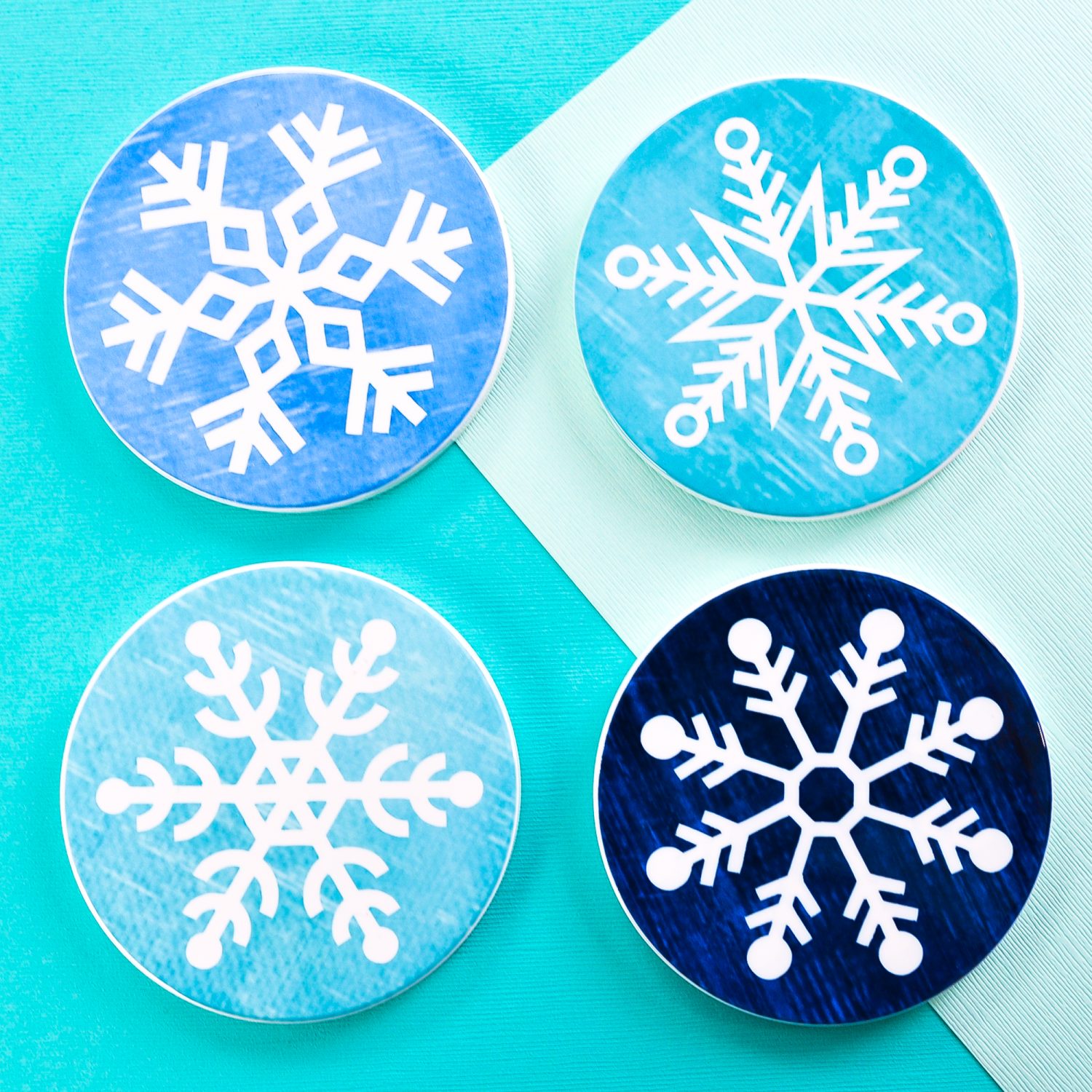 Four finished snowflake coasters on teal background
