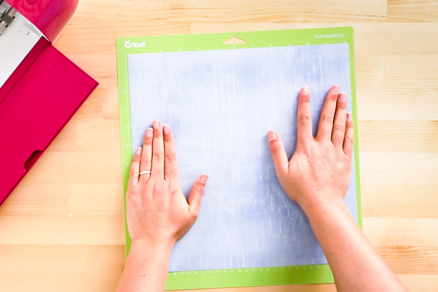 Hands putting Infusible Ink transfer sheet on a green cutting mat.