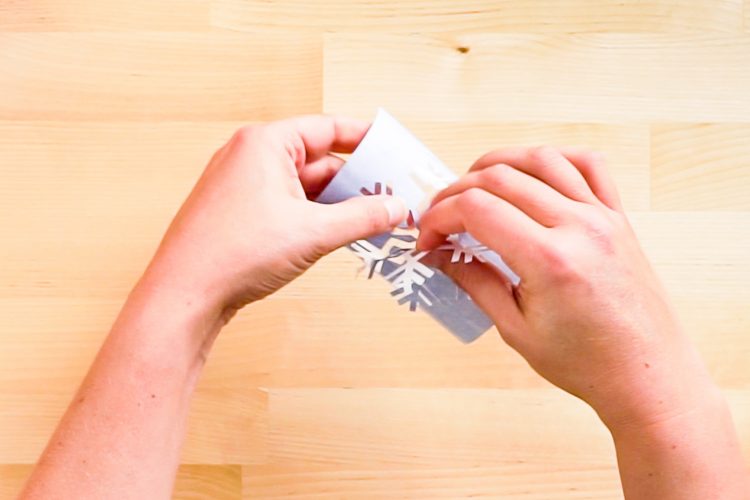 Person's hands weeding a snowflake from an infusible Ink transfer sheet