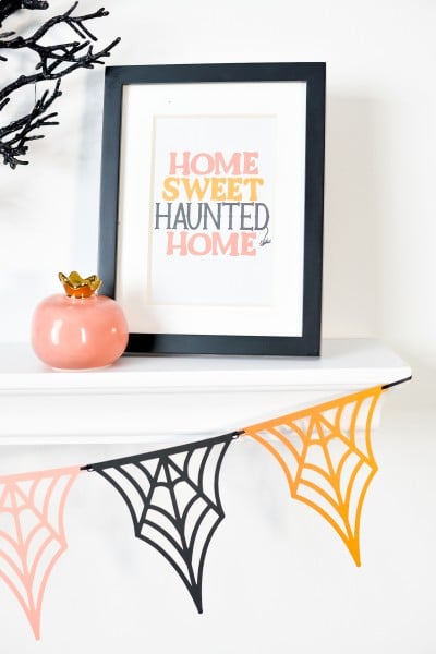 Spider web banner hanging from shelf with Halloween decorations