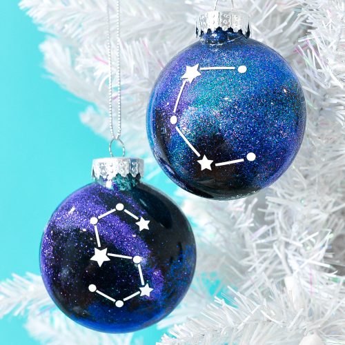 Finished constellation glitter ornaments hanging from white Christmas tree.