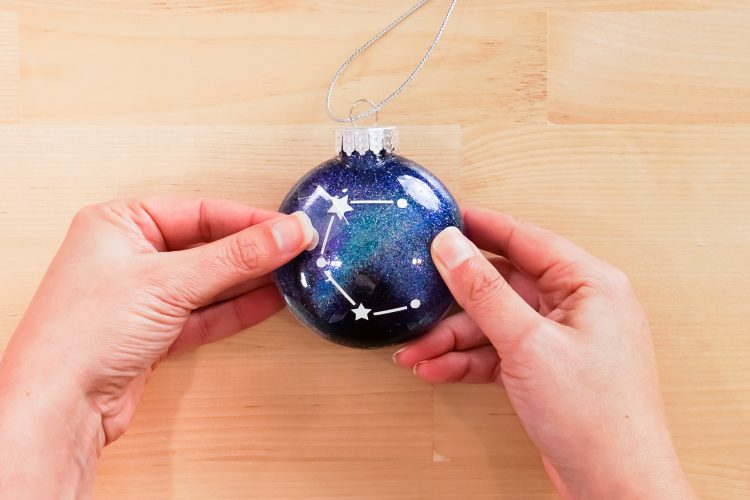 Hands removing transfer tape from vinyl on ornament