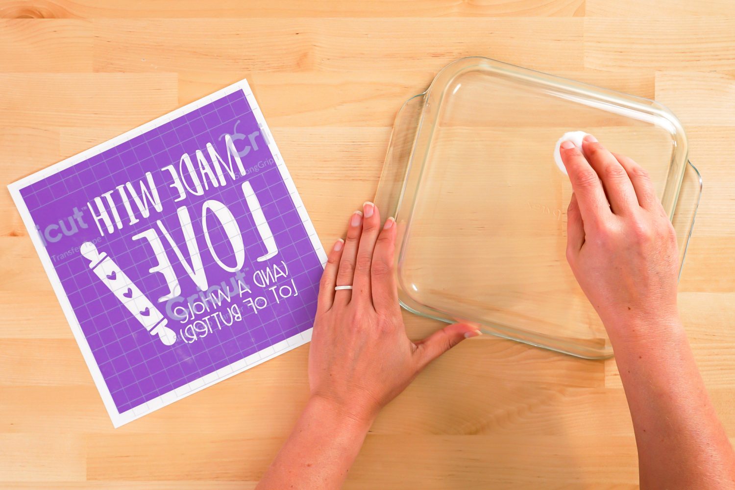 Hands cleaning the bottom of the casserole dish with cotton ball and alcohol.