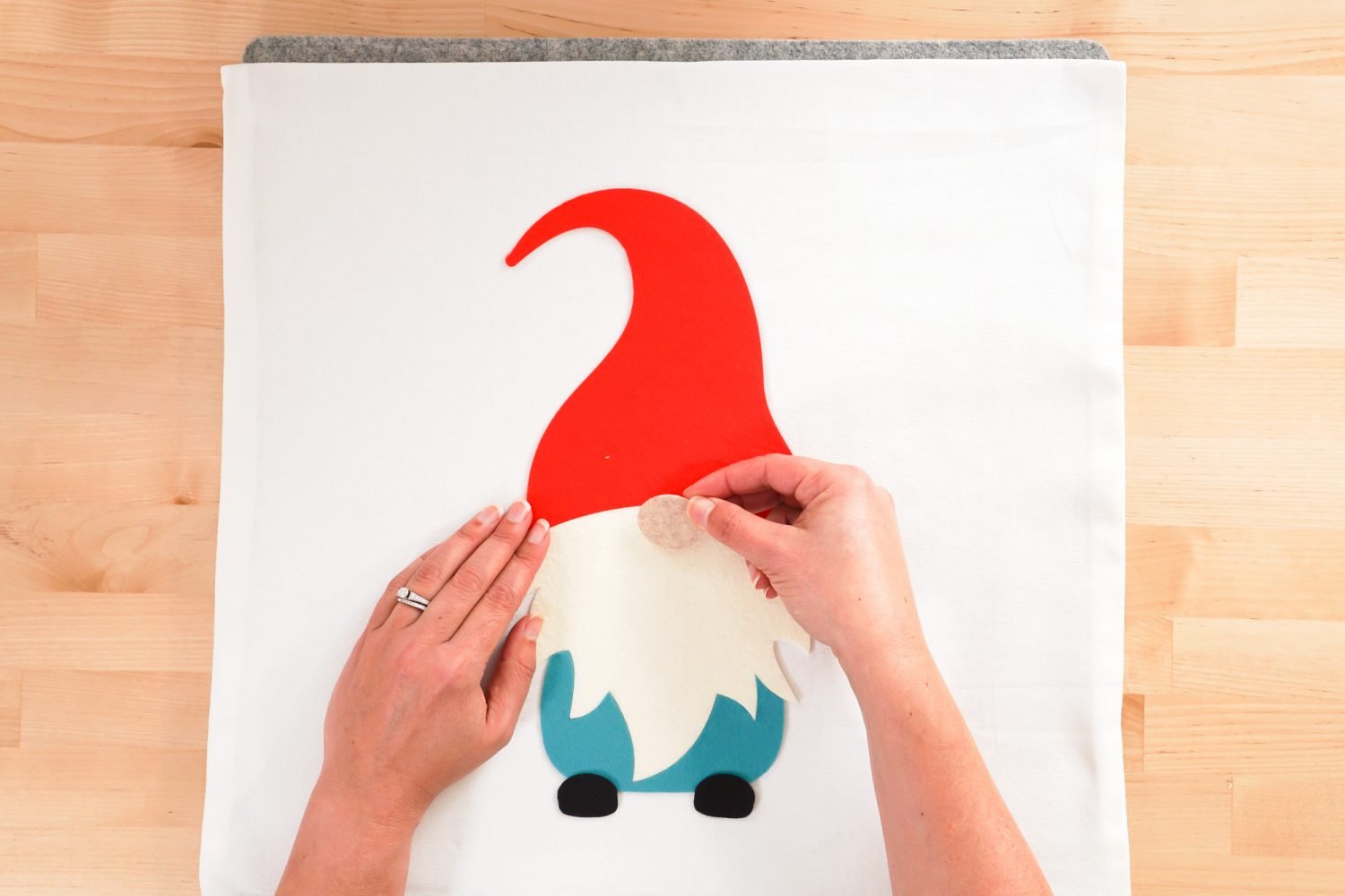 Hands placing all of the gnome pieces on the pillow.