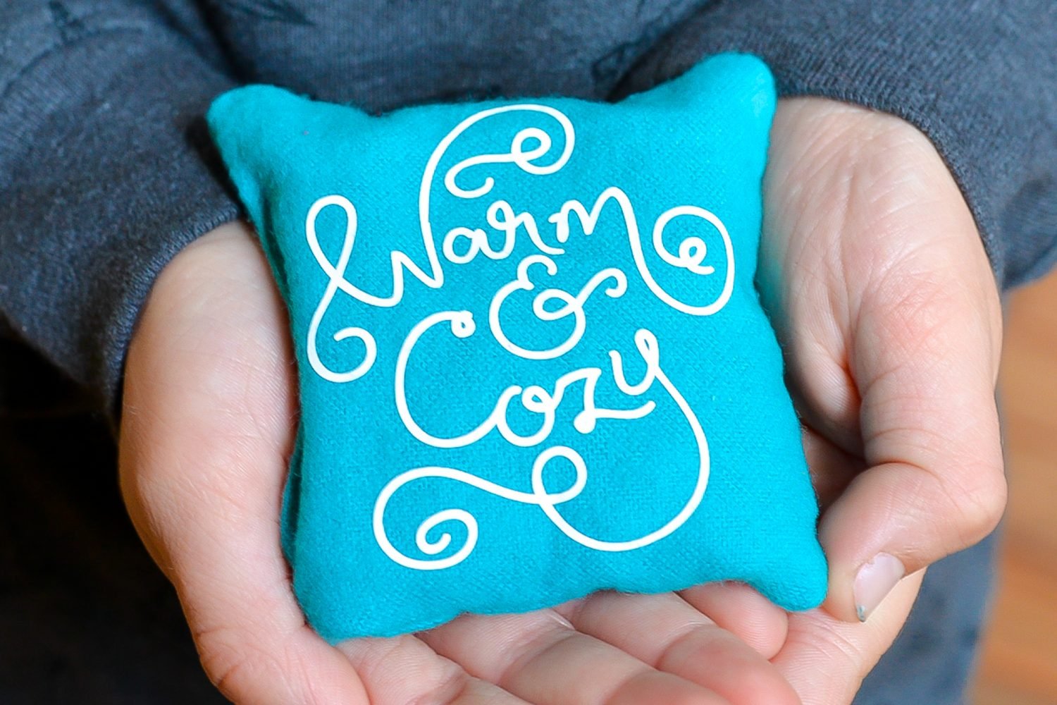Image of person holding a small pillow like hand warmer