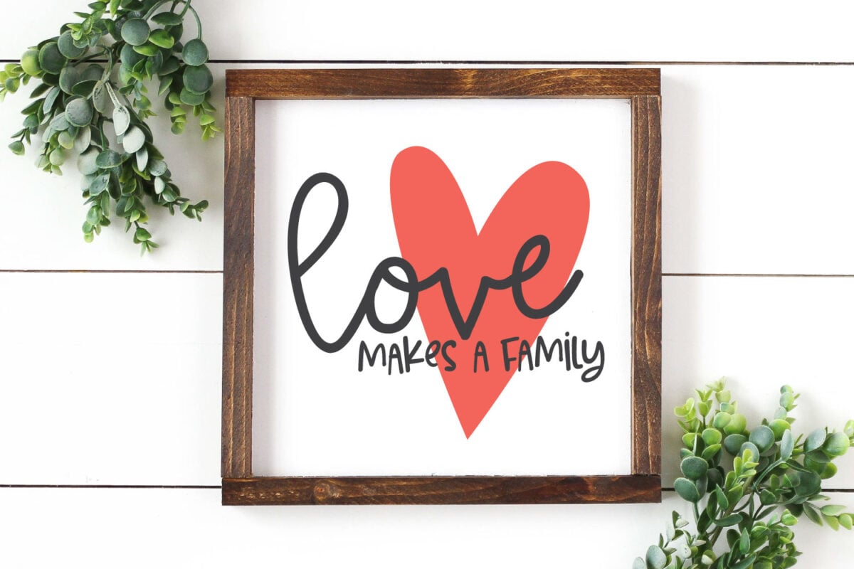 Love Makes a Family SVG on home decor sign with greenery