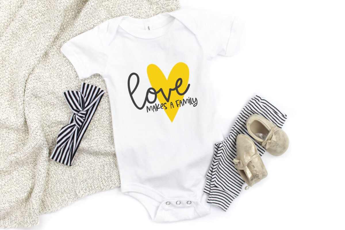 Love Makes a Family decal on onesie with baby shoes, headband, and blanket