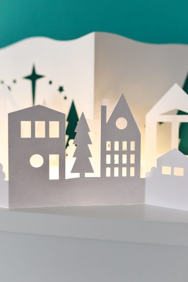 Papercut Christmas Village illuminated with fairy lights