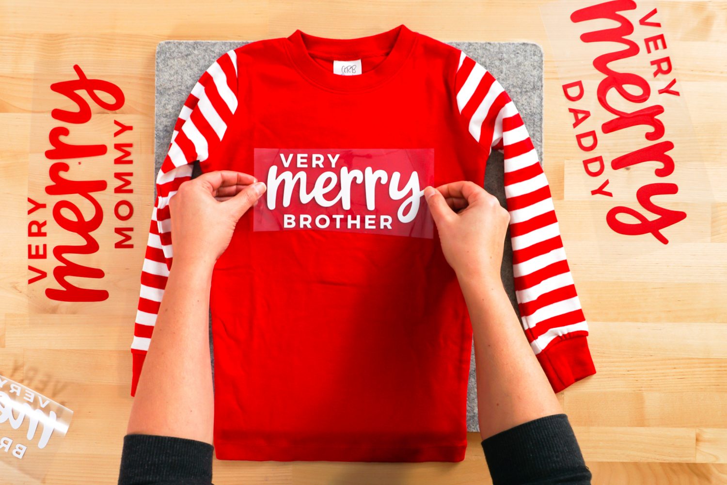 hands placing Very Merry Brother decal on shirt