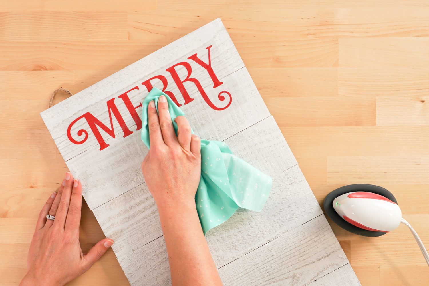 Hands using a piece of cotton to press MERRY onto the board