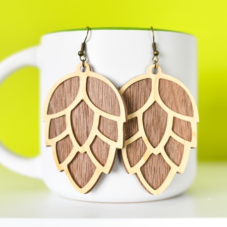 Finished pinecone earrings hanging from a mug