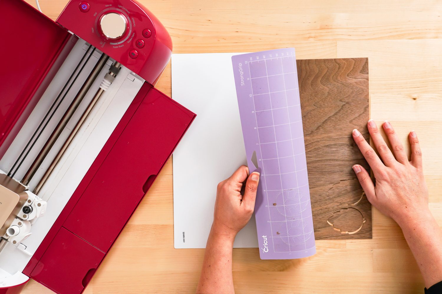 Hands bending the mat away from the project while holding down the veneer.