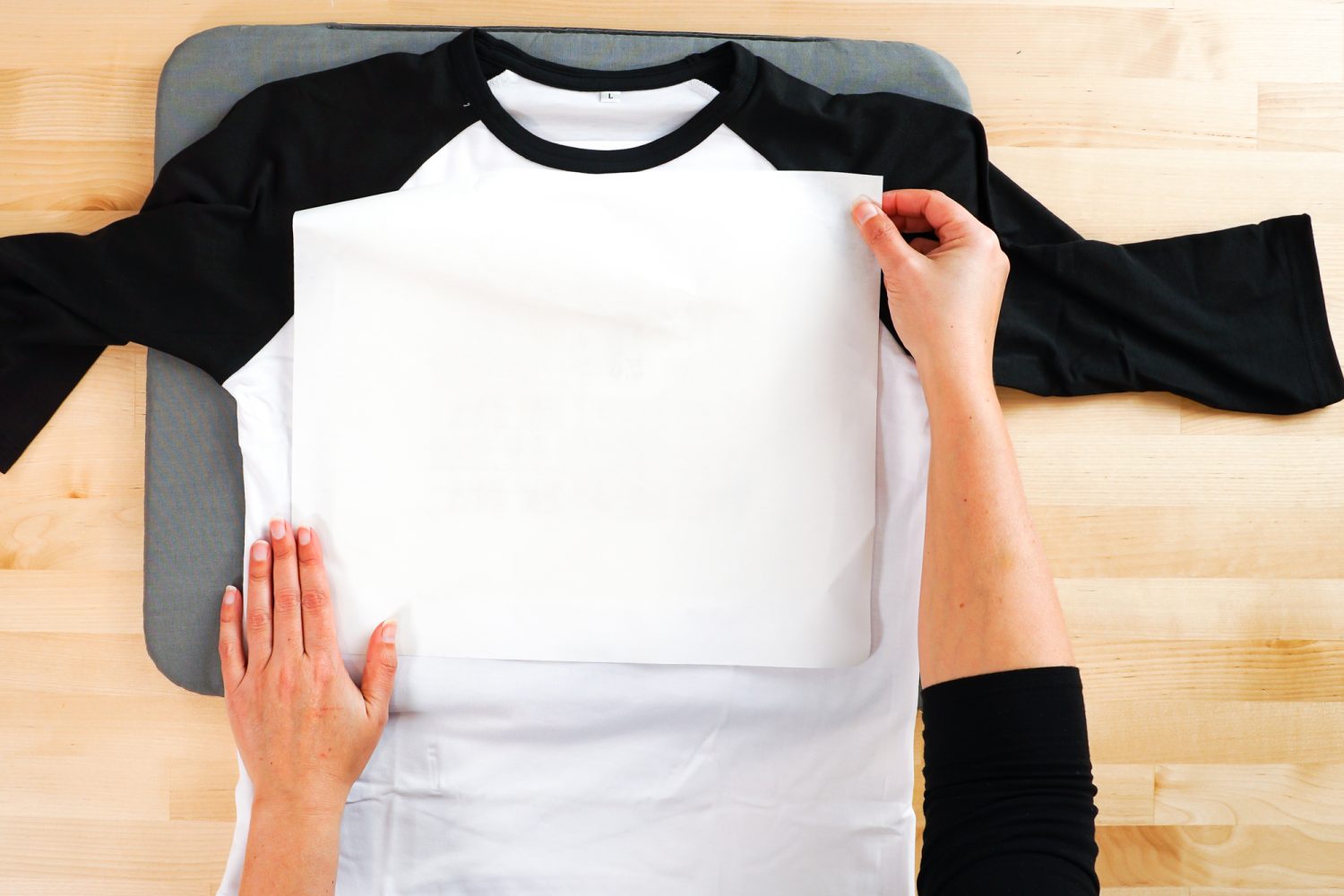 Hands placing the butcher paper on the Cricut Infusible Ink raglan.