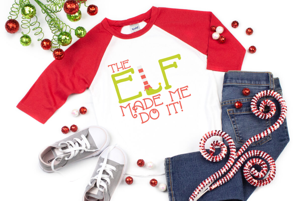 The Elf Made Me Do It SVG on a red and white raglan shirt