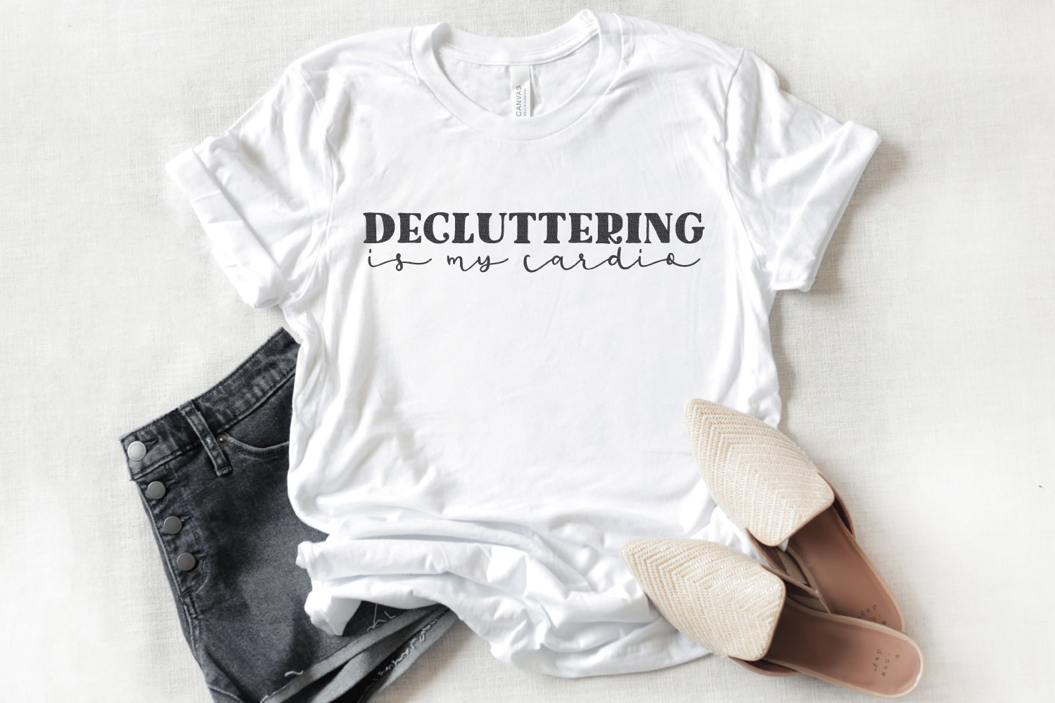 Decluttering is my Cardio quote on white t-shirt shown with a pair of shorts and flats
