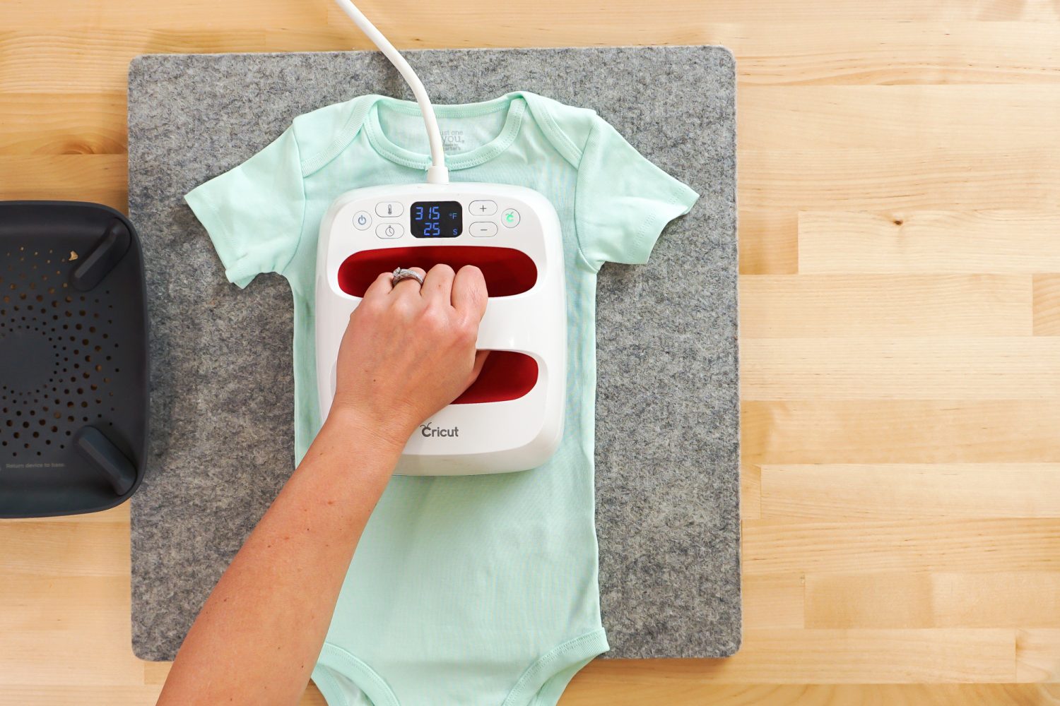 Overhead shot: hand pressing decal to the onesie with the EasyPress