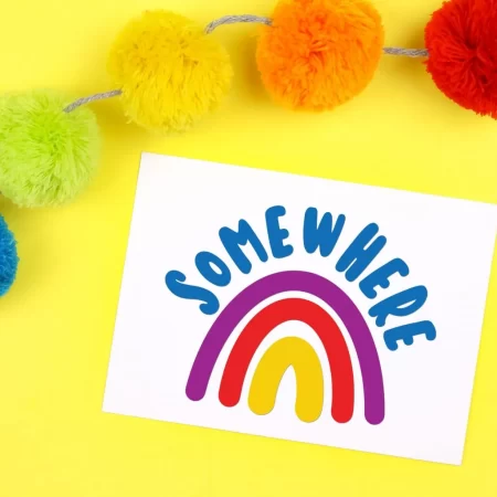 A white card with an image of a rainbow on it and the word Somewhere on the top of it